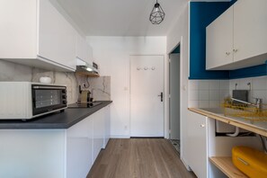 Eine kleine Küche mit weißen Schränken, einer Mikrowelle und einer Holz Arbeitsplatte.