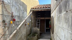 A narrow alleyway with a concrete wall, a tiled roof entrance, and a ladder. - Le Refuge Loti - 200m de la Plage (Port-des-Barques)