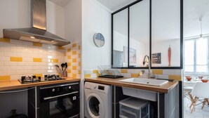 A compact kitchen with a built-in oven, a washing machine, and a sink. - Le Refuge Loti - 200m de la Plage (Port-des-Barques)
