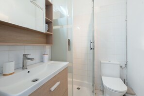 Un baño moderno con lavamanos, espejo e inodoro.