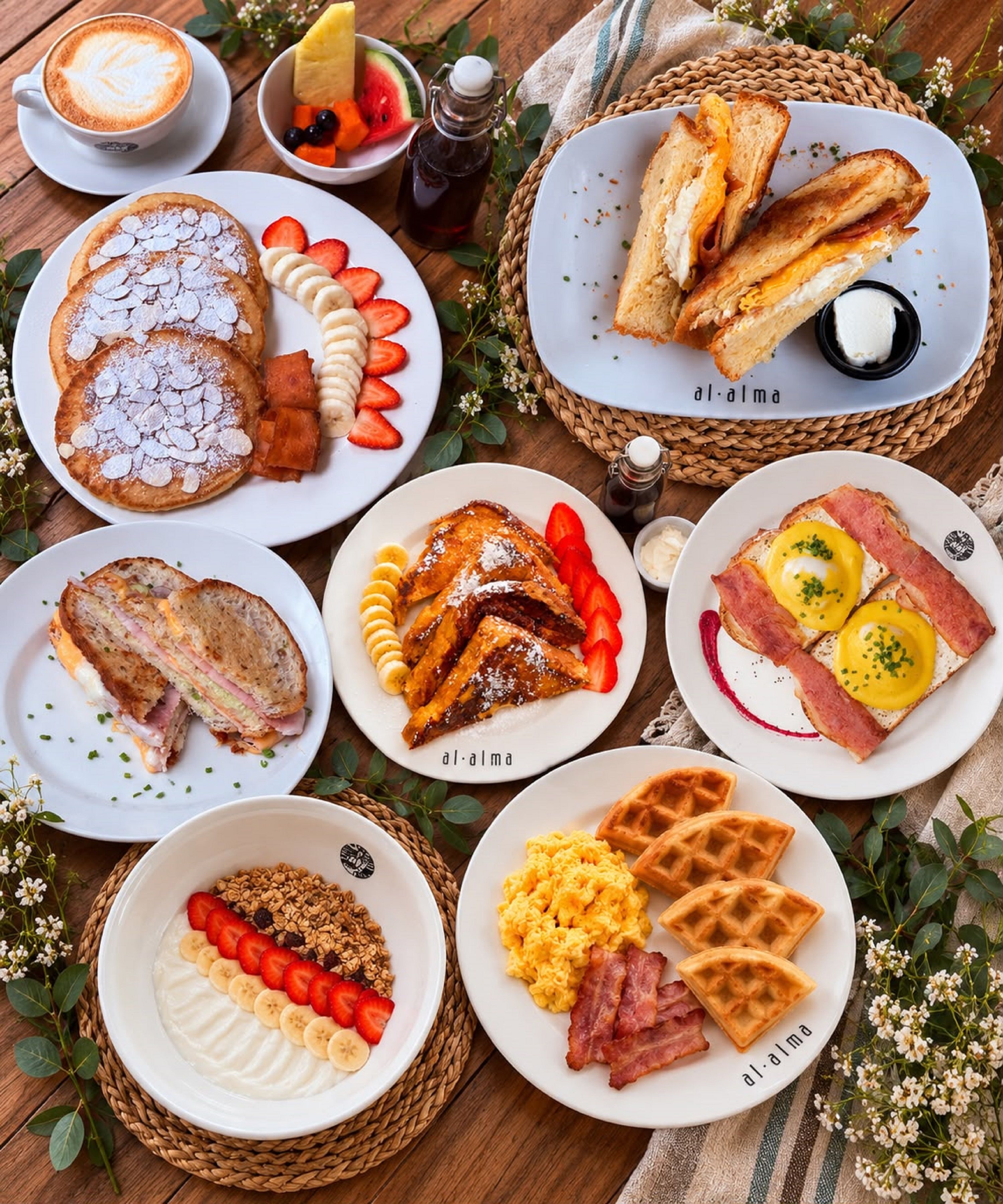 Variedad de platos de desayuno, incluyendo panqueques, huevos, gofres y tostadas, dispuestas en platos y cestas.