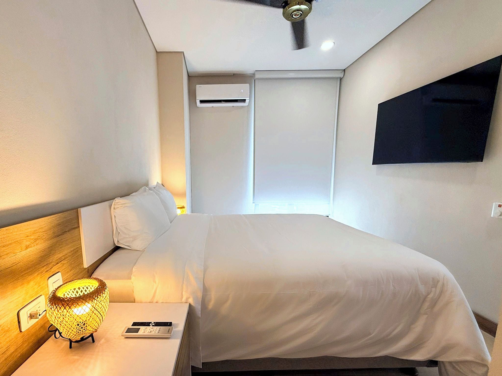 Une chambre d’hôtel équipée d’un lit, d’une table de chevet, d’une lampe et d’un téléviseur fixé au mur.