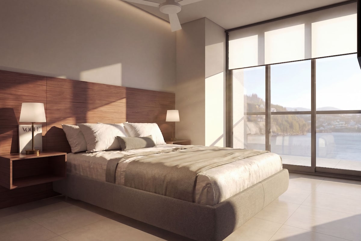 A modern bedroom with a large bed, nightstands, and a view of a body of water through large windows.