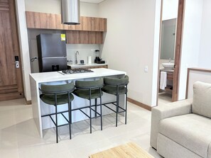 A modern kitchen with a central island, bar stools, a refrigerator, and a sink. - Nuruma Suites by Avia Suites (Santa Marta)