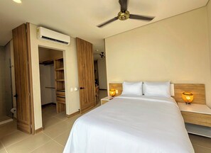 Ein Hotelzimmer mit einem Bett, Nachttischlampen, einem Deckenventilator und einem offenen Kleiderschrank.