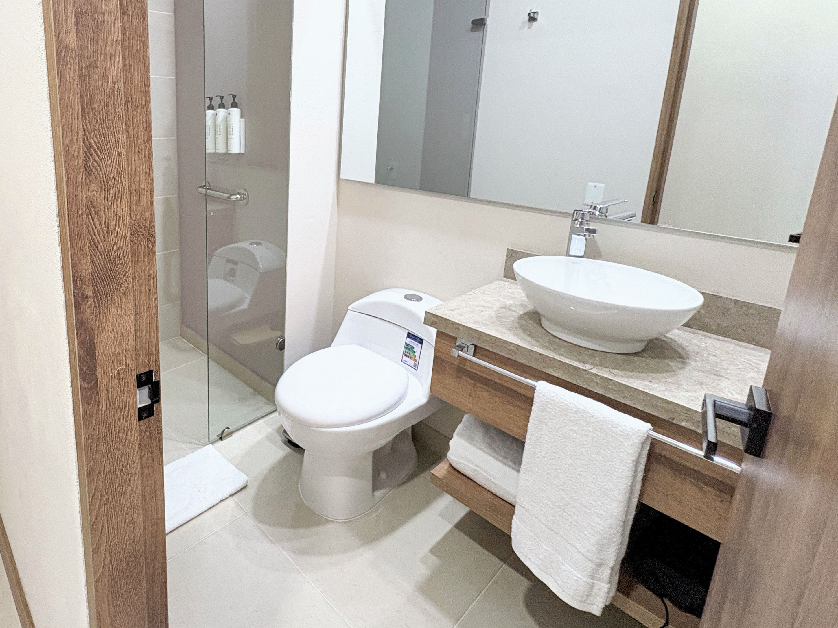 Une salle de bain moderne avec des toilettes, un lavabo et un miroir.