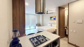 A modern hotel room with a kitchenette, a bed, a bathroom, and a balcony.
