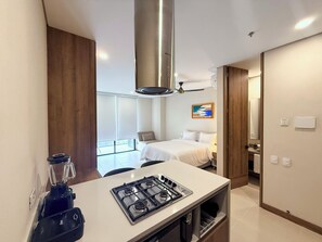 A modern hotel room with a kitchenette, a bed, a bathroom, and a balcony.