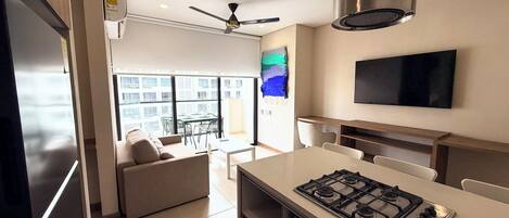 A modern kitchen with a gas stove, a ceiling fan, and a flat-screen TV mounted on the wall.