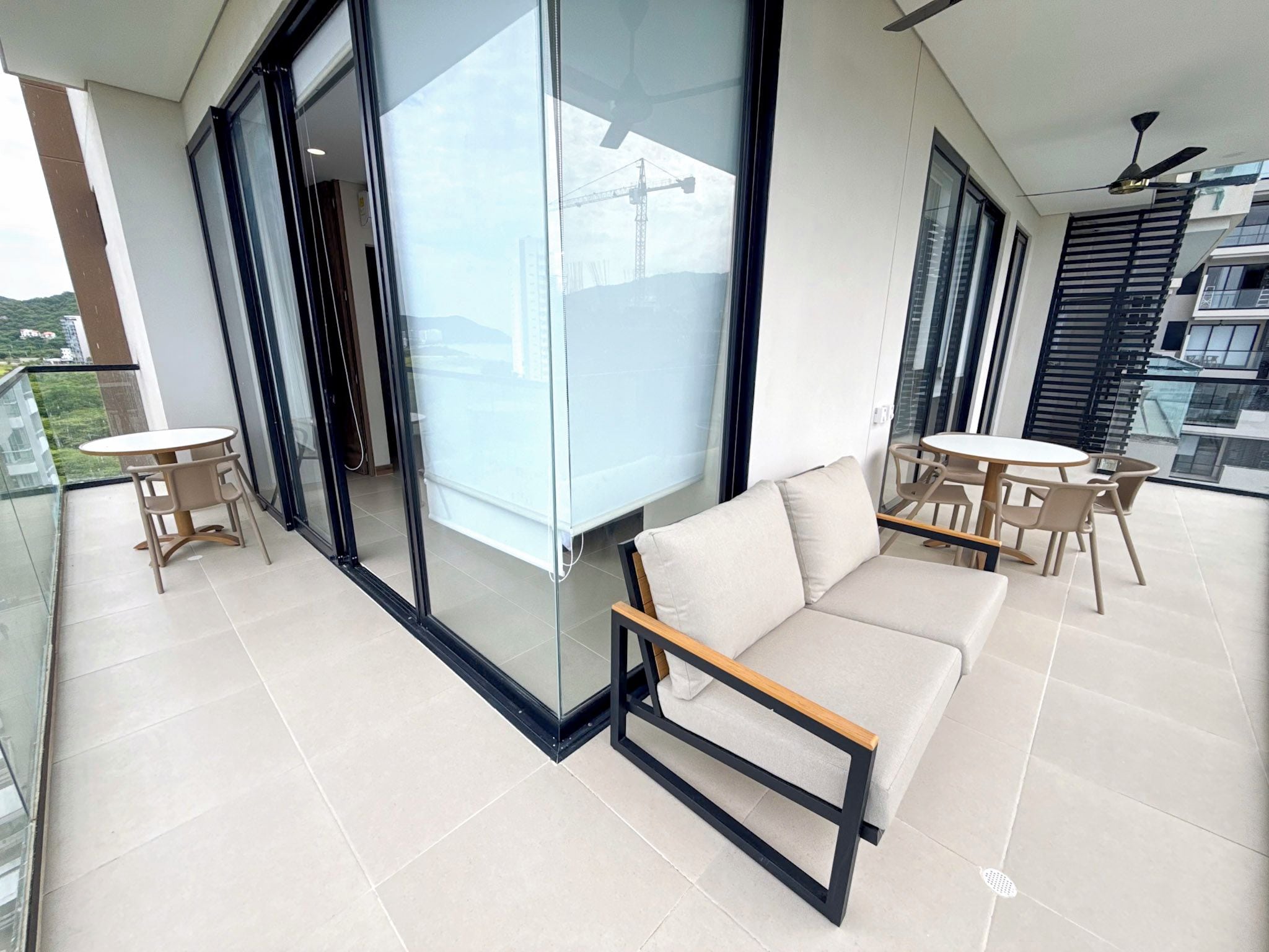 A modern balcony with a sofa, chairs, and a table.