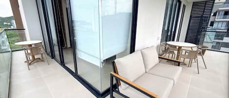 Ein moderner Balkon mit einer Couch, Stühlen und einem Tisch.