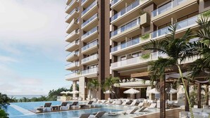 A multi-story hotel with a pool area, lounge chairs, and palm trees. - Nuruma Suites by Avia Suites (Santa Marta)