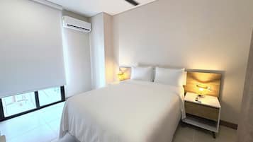 A hotel room with a large bed, bedside lamps, an air conditioning unit, and a ceiling fan.