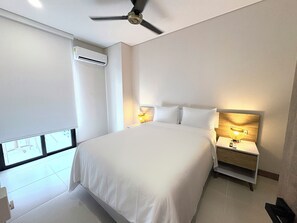 Une chambre d’hôtel avec un grand lit, des lampes de chevet, un climatiseur et un ventilateur de plafond.