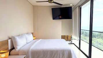 Ein modernes Hotelzimmer mit einem großen Bett, einem Deckenventilator, einem flachbildfernseher an der Wand und einem Balkon mit Blick.