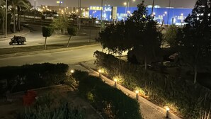 Een nachtzicht van een straat met lantaarns, een blauw gebouw met een IKEA-bord en een aangelegde omgeving met bomen en een pad.