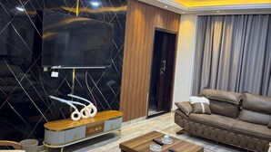 Een moderne woonkamer met een flatscreen televisie, leren banken, een bijzettafeltje en een behang met patroon.