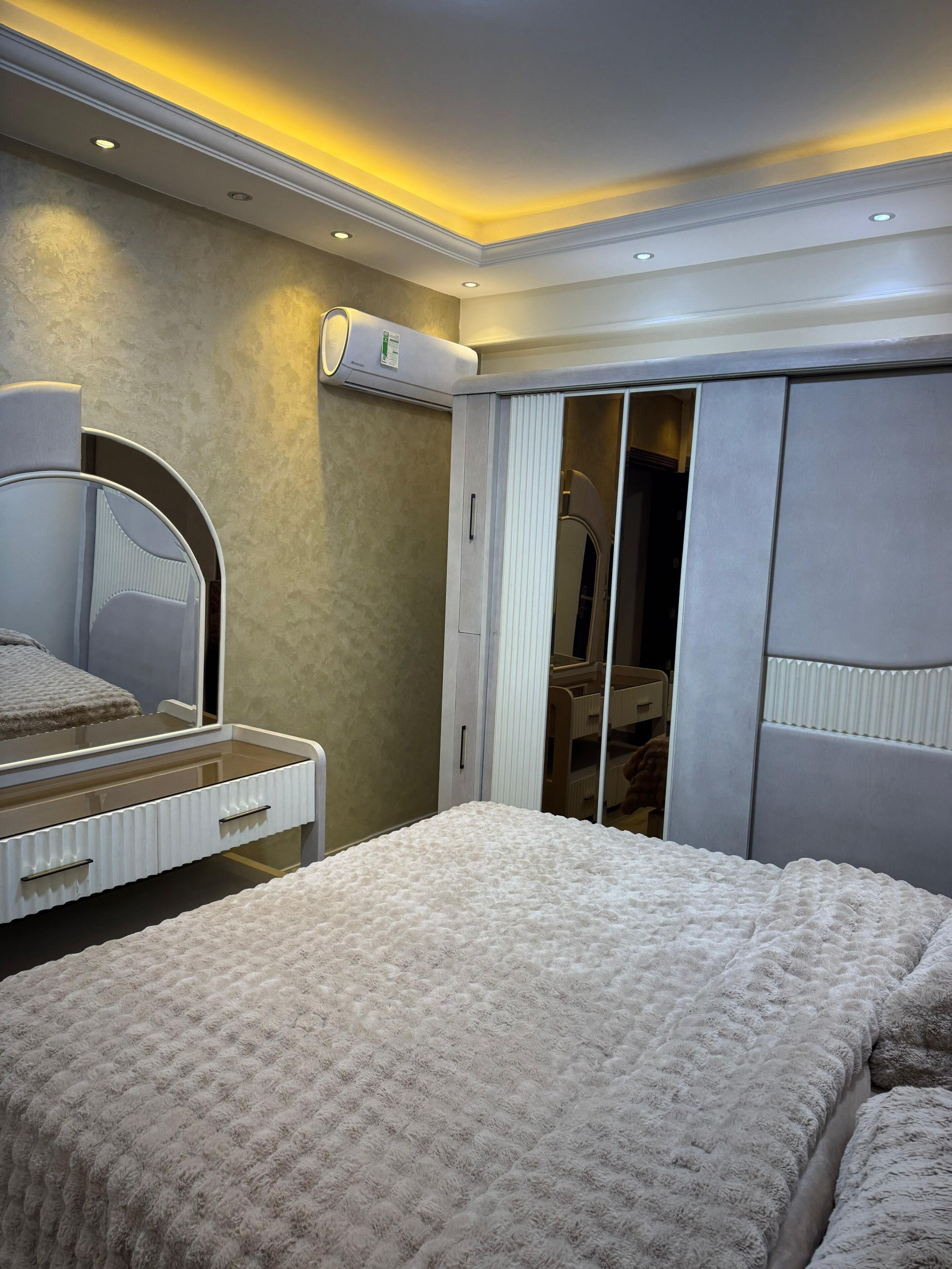 A bedroom with a bed, a dresser, a mirror, and a wardrobe.