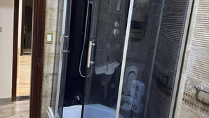 Een douchecabine met een glazen deur, een zichtbare douchekop en een toilet.