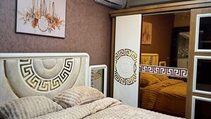 Een slaapkamer met een bed, een wandairconditioner en een deur met een spiegel.