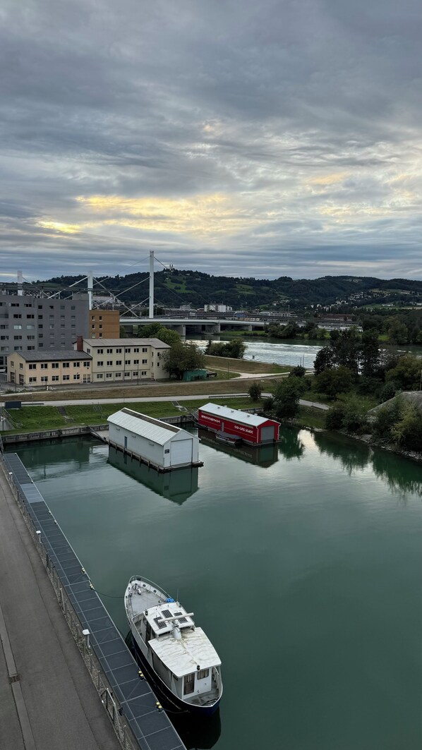 Un río con un bote amarrado en un muelle, un puente al fondo y edificios a lo largo de la orilla.