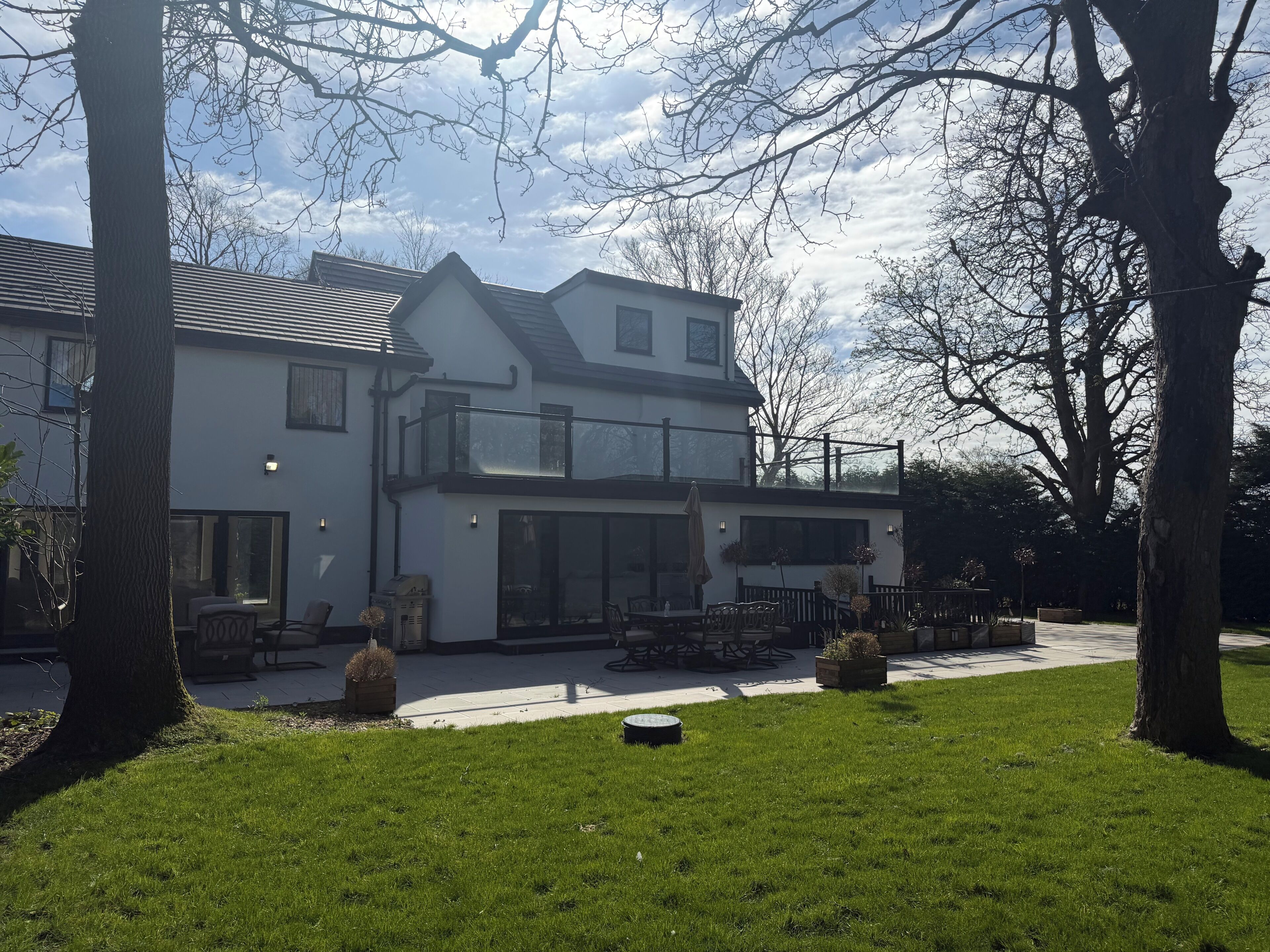 A two-story house with a balcony, a patio area, and a lawn.