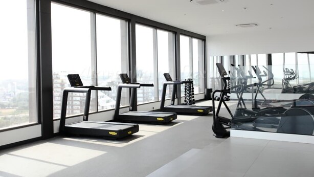 Een moderne sportschool met grote ramen, loopbanden en fitnessapparatuur.