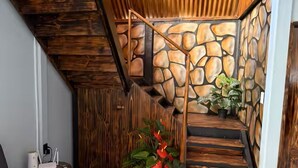 Eine Treppe mit Holzsitzen und einer Steinwand, ein graues Sofa und eine Vase mit roten Blumen.