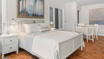 A bedroom with a large bed, bedside tables, a desk, and chairs.