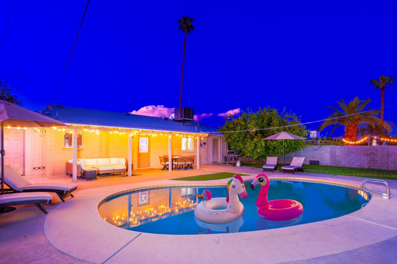 Ein Garten mit Schwimmbad, Liegestühlen und einer überdachten Terrasse.