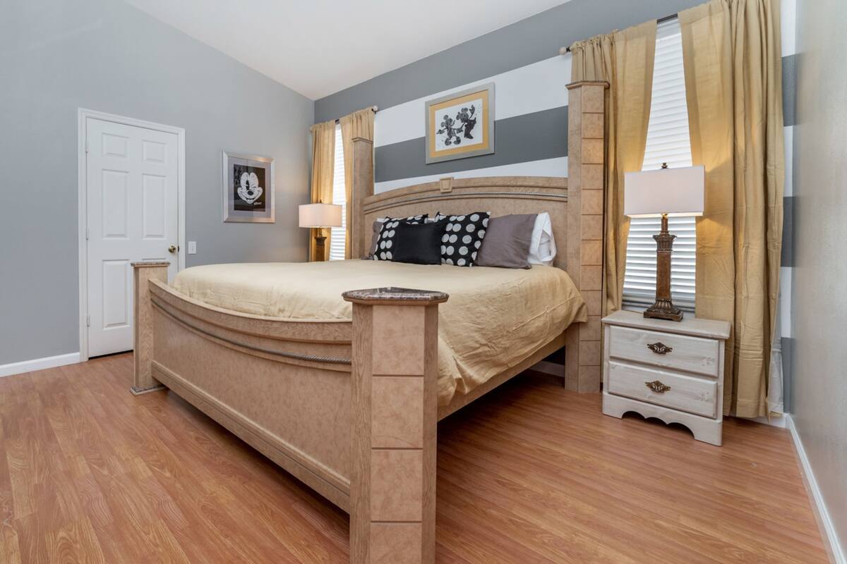 Une chambre à coucher avec un lit, des tables de chevet, une porte et une fenêtre avec des rideaux.