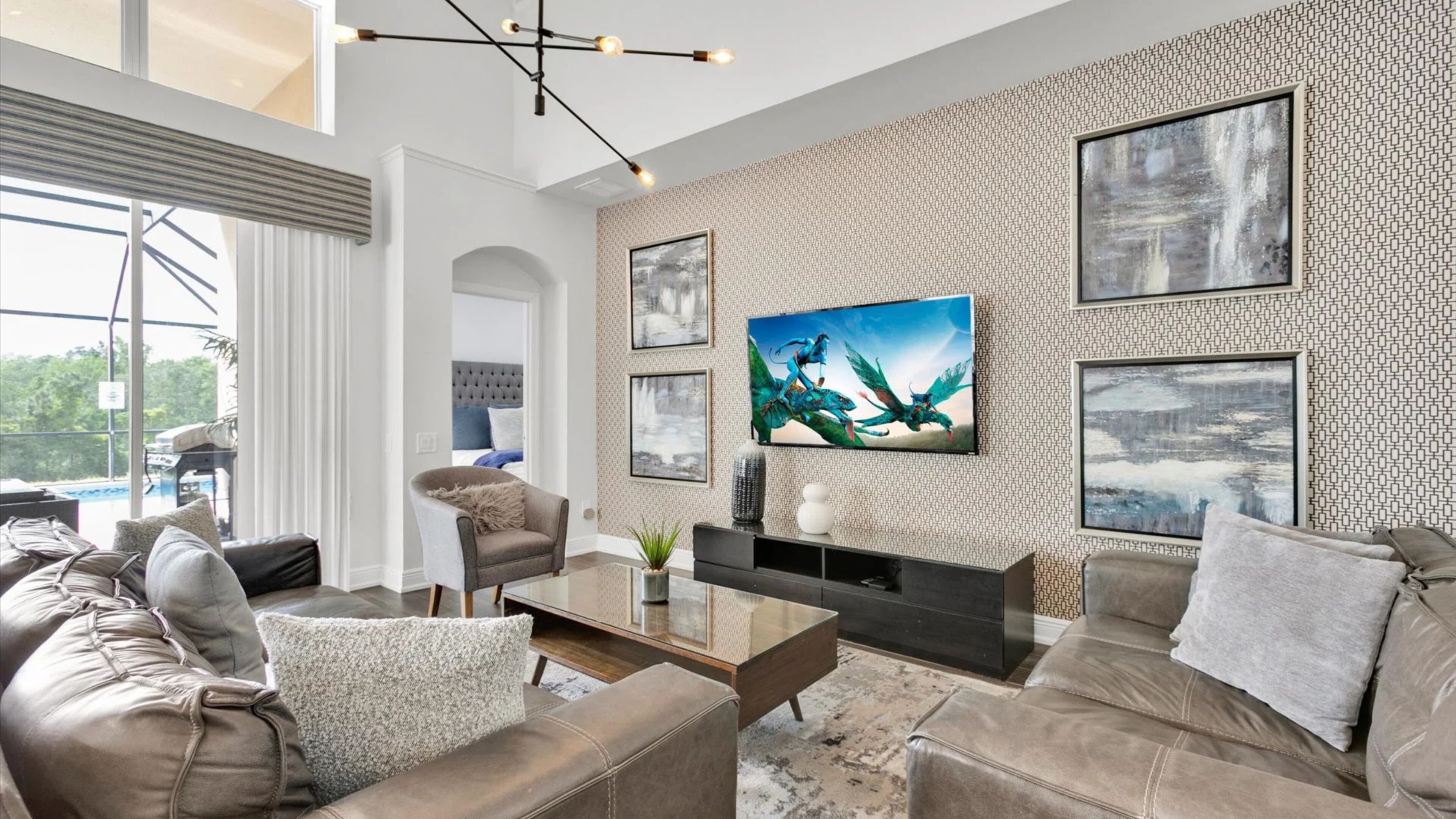 A modern living room with a large TV, comfortable seating, and a patterned wall.