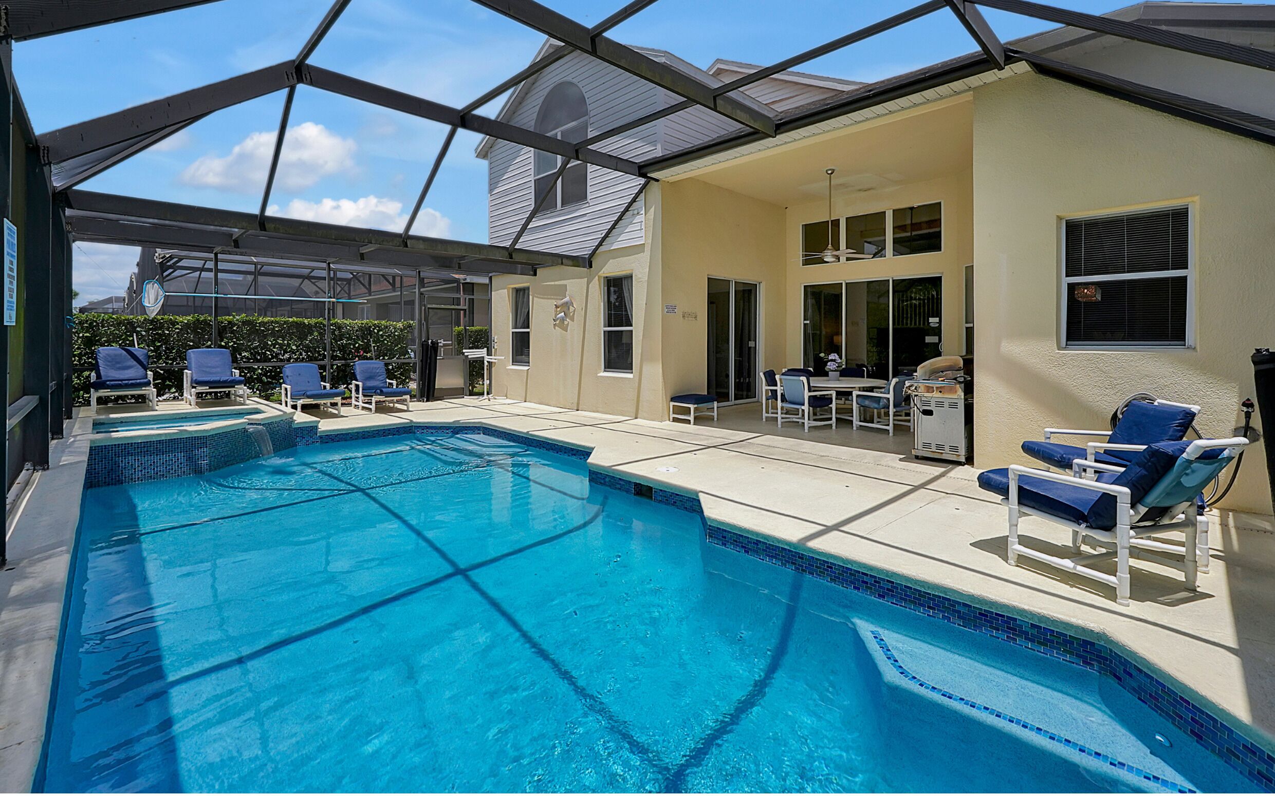 A covered swimming pool with lounge chairs and a patio area.