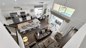 A spacious living area with a dining table, sofa, and a staircase leading to an upper level.