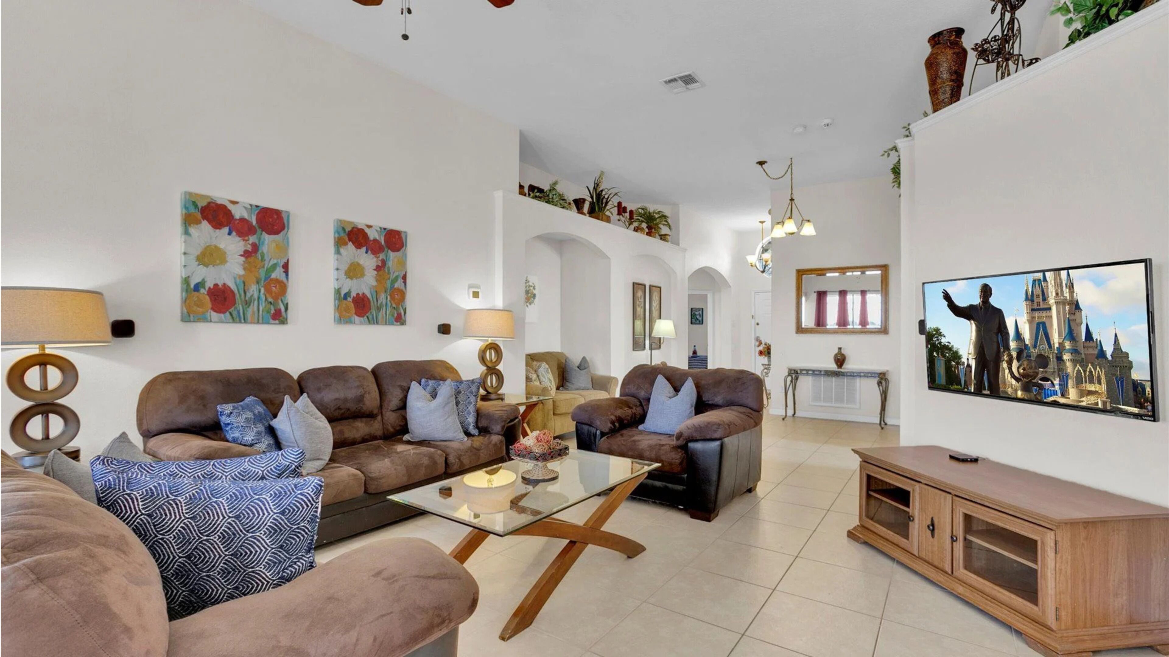 A spacious living room with sofas, a coffee table, and a TV displaying a castle.