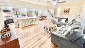 A modern kitchen with a central island, a dining area with a sofa, and a ceiling fan.
