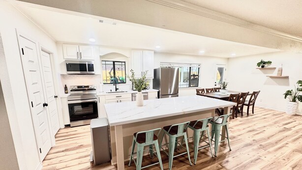 A spacious kitchen with white cabinets, a large island, and bar stools.