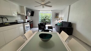 Cocina compacta con una mesa de comedor, sillas, ventilador de techo y vistas al exterior.