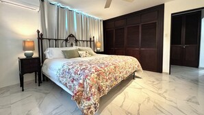 Un dormitorio con cama, mesita de noche, lámpara, ventilador de techo y armario.