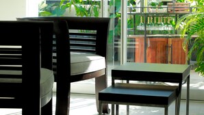 Un espacio de estar moderno al aire libre con un separador de vidrio, una mesa de madera y sillas.