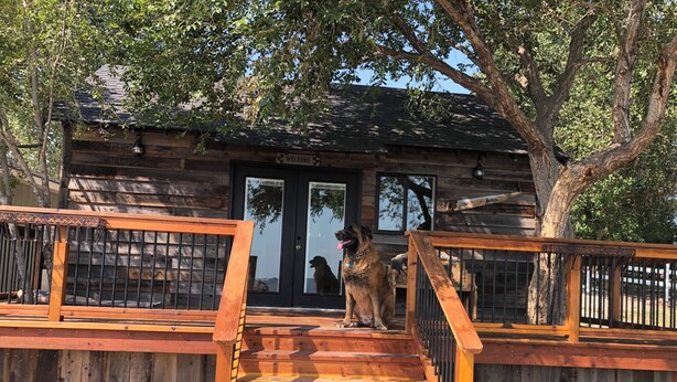 A wooden cabin with a wooden deck and a staircase leading to a black door. - Rustic Updated Cabin located on the Cliffs of the Snake River (Marsing)