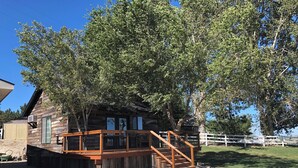 A wooden cabin with a deck and stairs, surrounded by trees and a white fence. - Rustic Updated Cabin located on the Cliffs of the Snake River (Marsing)