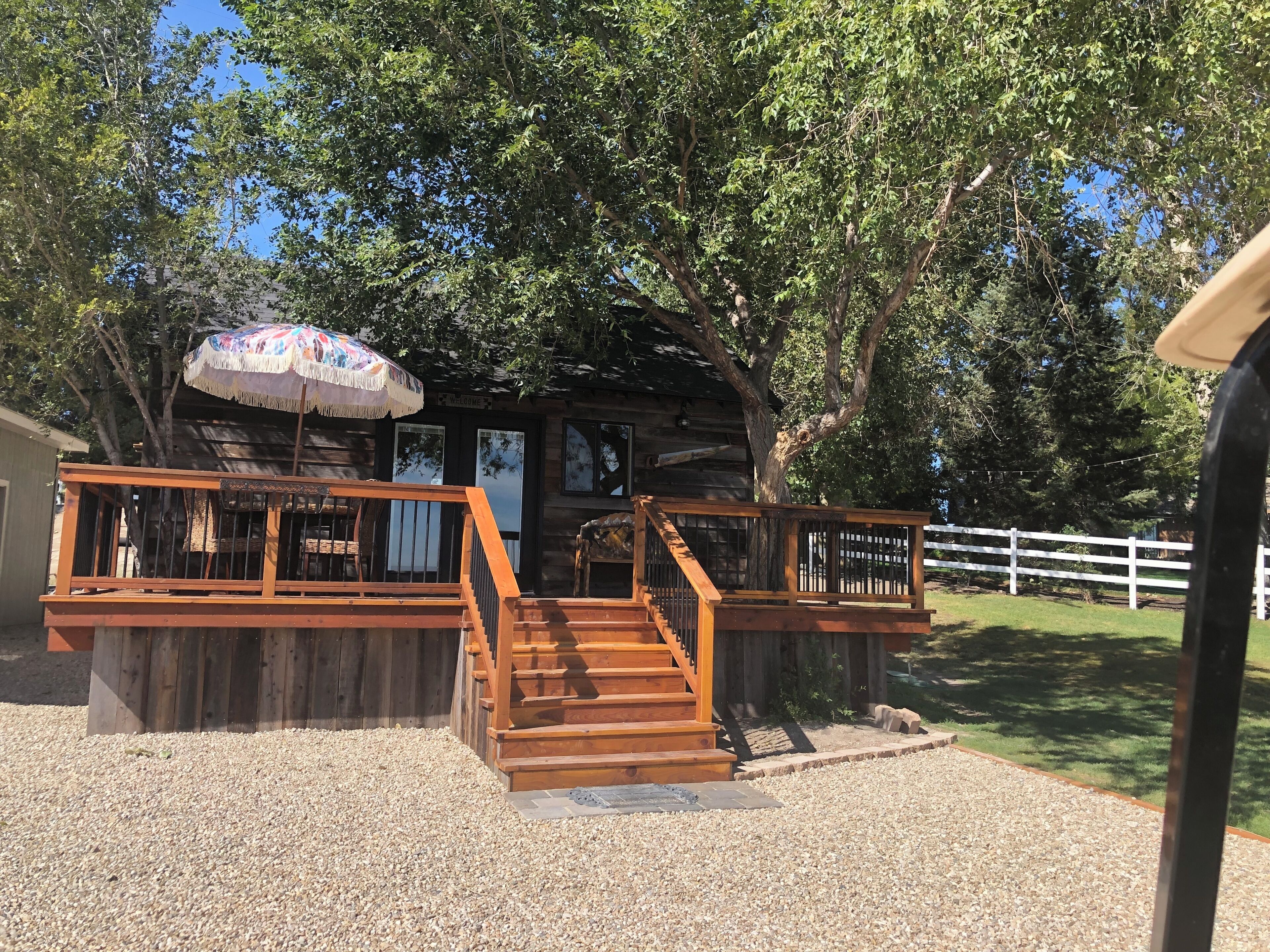 A wooden cabin with a porch, a staircase, and a welcome sign.