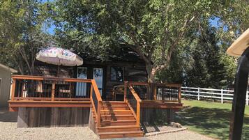 A wooden cabin with a porch, a staircase, and a welcome sign.
