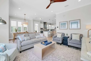 A spacious living area with a sofa, coffee table, and a dining area with a kitchen in the background. - Freedom On 30A by Stay on 30a (Inlet Beach)