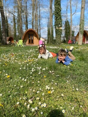 Two children lying on grass with tents in the background. - ZEcamping 2 étoiles piscine couverte pet friendly sauna locatif 9m2 3 pers (Bar-sur-Aube)