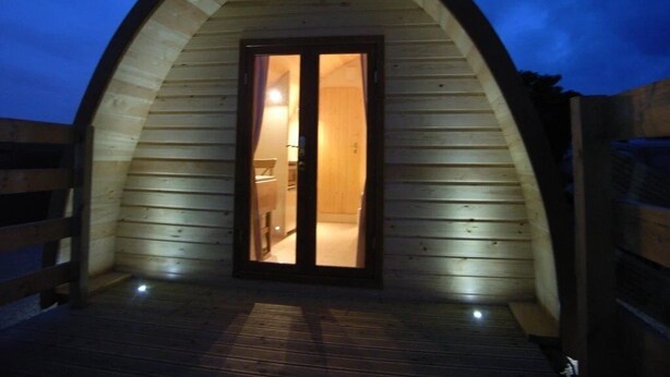 Una estructura de madera con arco y una puerta que da a un espacio interior.