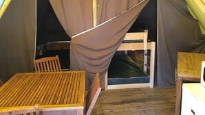 Ein Zelt mit Bett, Tisch und Stuhl.