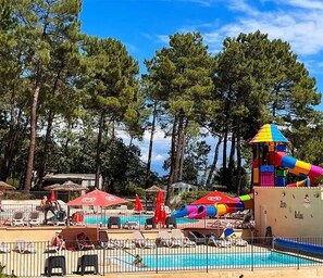 Ein Poolbereich mit Liegestühlen, Sonnenschirmen und einer Wasserrutsche.