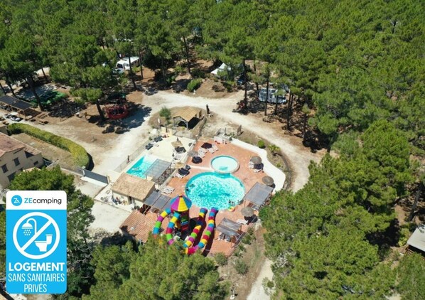 Luchtbeeld van een camping met een zwembad, lounge stoelen en een aangewezen plek voor campers.
